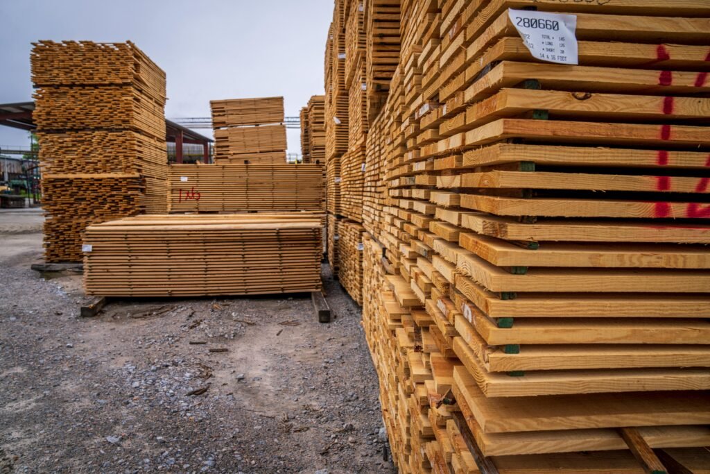 High stacks of wooden planks stored outdoors in a lumber yard.